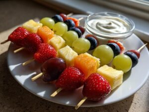 Close-up of colorful fruit skewers featuring strawberries, pineapple, grapes, and blueberries, served with a side of creamy dip.