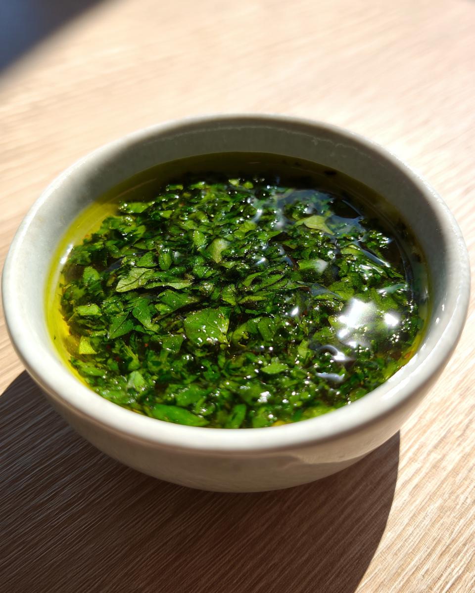 Close-up of vibrant green, freshly chopped mint leaves suspended in liquid for homemade mint sauce, sitting in a small white bowl.
