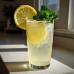 A tall glass filled with bubbly sparkling lemonade, garnished with fresh mint and lemon slices.