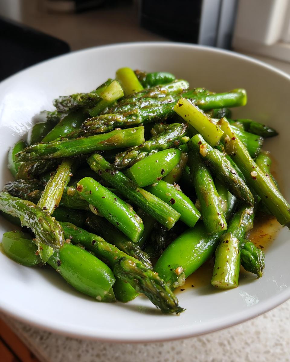 Close-up of bright green asparagus pieces seasoned and served in a white bowl, part of a Spring vegetable saute.