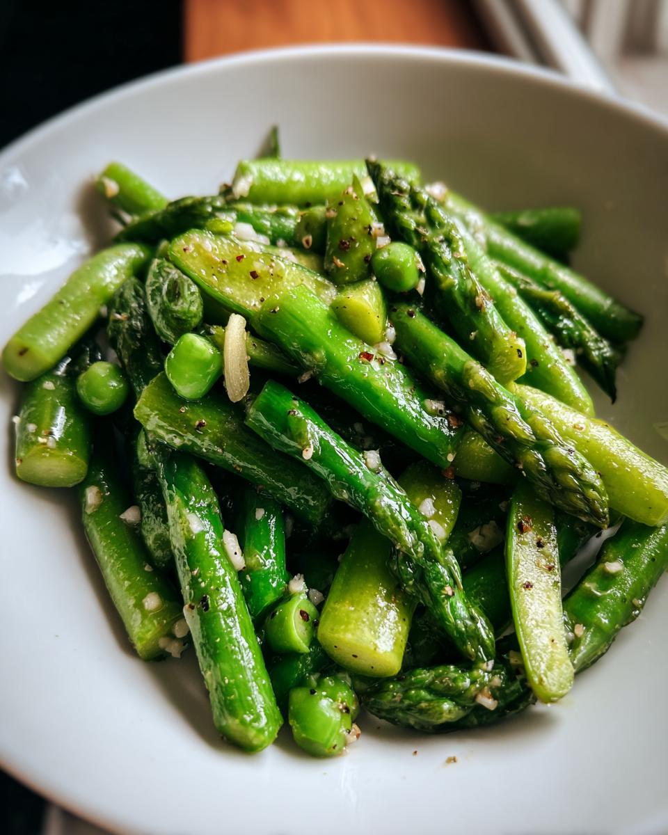 Close-up of bright green asparagus spears and peas seasoned with garlic and pepper in a Spring vegetable saute.