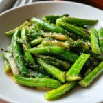 Close-up of a bright green Spring vegetable saute featuring snap peas and asparagus tossed with garlic and pepper.