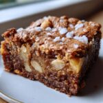 A close-up of a rich, chewy white chocolate blondies square topped with flaky sea salt and visible white chocolate chunks.